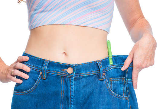 The result of an effective diet, a slim figure in large jeans closeup