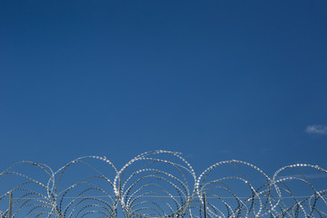 Barbed and razor wire against blue sky