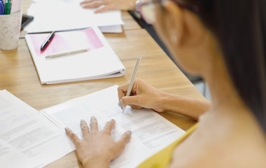  Businesswoman writing on document sitting in the office