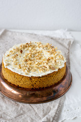 Gluten and sugar free Carrot banana cake decorated with nuts and cream cheese on textile background. Vegan food concept for good breakfast or dinner