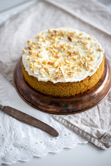 Gluten and sugar free Carrot banana cake decorated with nuts and cream cheese on textile background. Vegan food concept for good breakfast or dinner