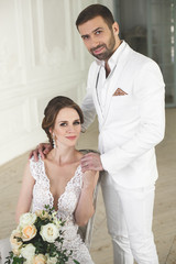 Chic wedding couple groom and bride posing in a white Studio. Happy couple laughing. White dress....