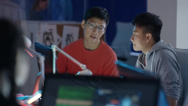  Game designers looking at computer screen & discussing ideas for the project