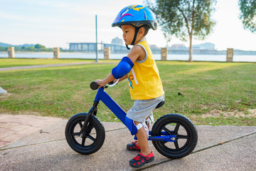 A cute little boy riding a balance bike in the park.