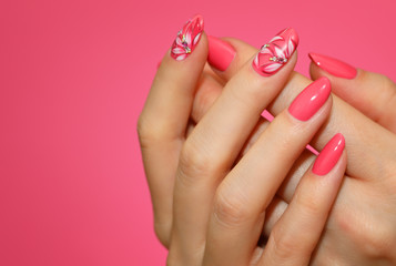 Manicured woman's nails with pink nailart with flowers.