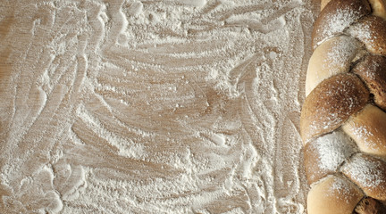 braided bread lies on a wooden table with flour