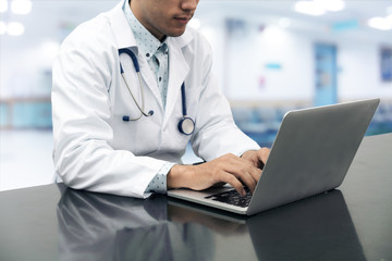 Doctor working on desk with laptop