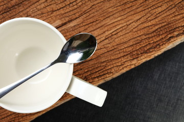 Coffee cup and spoon put on hard wood floor.