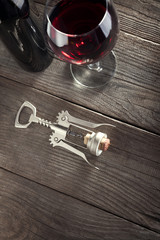 Corkscrew and a glass of wine on an old wooden table © Chepko Danil