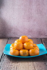 Oranges fruits placed on the plate on a wooden floor.
