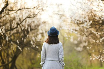 Girl in a green hat in a blooming garden