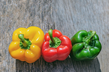 red paprika, yellow paprika and green paprika on wood background.selective focus