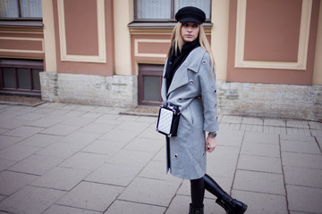 Young, hip and attractive blonde walking around the city, girl in a stylish hat and a gray coat