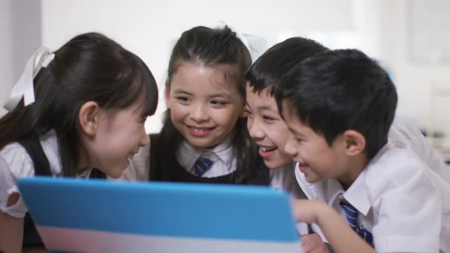  Happy group of children looking at computer in school classroom