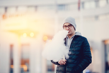 vaping man holding a mod device. cloud of vapor. Vape. high contrast and monochrome color tone.