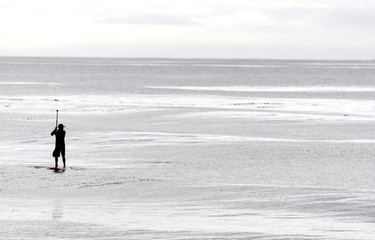 Fototapeta na wymiar A lone Paddle-boarder glides through a calm sea near Goleta, CA, USA.