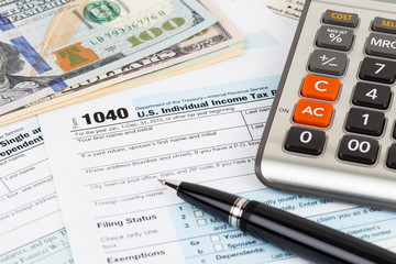 Tax form with calculator, pen, and dollar banknote