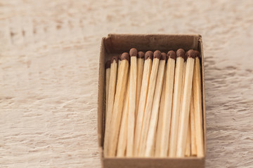 The matches are in a cardboard box on a wooden surface. A lot of matches in a box. Macro.