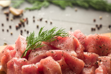 Juicy raw meat with spices, pepper, sea salt and herbs lies on a dark wooden background