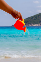 Female hand pours water from a children's plastic watering can. Andaman sea, Similan Islands