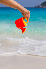 Female hand pours water from a children's plastic watering can. Andaman sea, Similan Islands