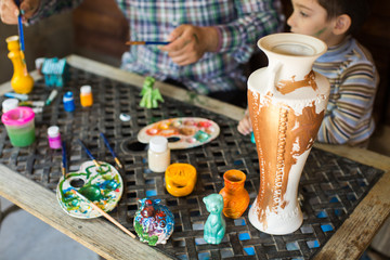 Father and son paint a vase