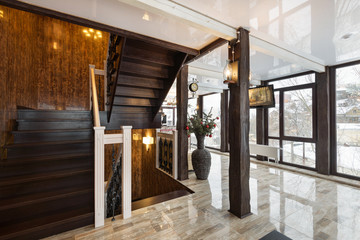 spacious bright hall of the hotel with panoramic windows and a beautiful wooden staircase