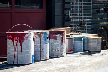 Old Paint Buckets Cans in front of an old garage