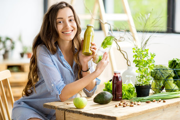 Beautiful happy woman sitting with healthy green food and drinks at home. Vegan meal and detox concept