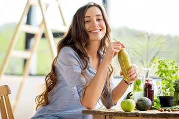 Beautiful happy woman sitting with drinks and healthy green food at home. Vegan meal and detox...