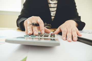 Asian Business woman using a calculator to calculate the numbers