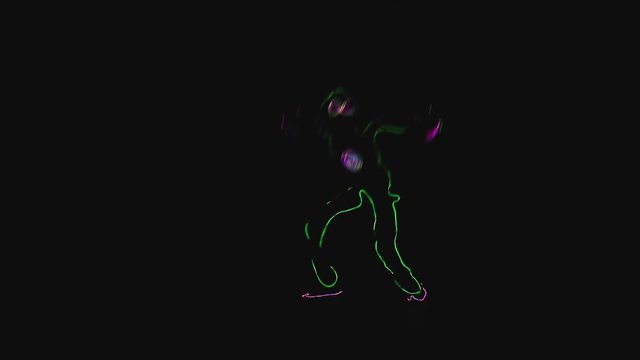 The glowing silhouette of an alien dances hip hop in the dark. Ful HD.
