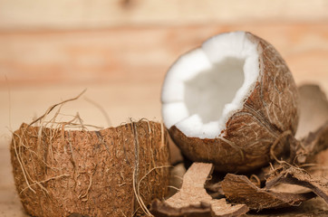 Broken coconut with coconut milk, sugar cubes and vintage old wooden background.