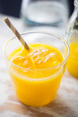 Orange juice with ice and grey striped straw