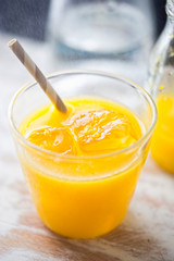 Orange juice with ice and grey striped straw
