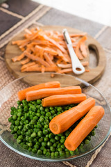 Cooked green peas with cooked carrot on the wooden board