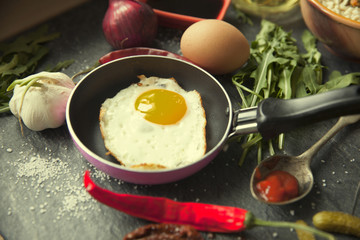 Table with food in breakfast or lunch: omelette, cabbage, oil, chili, ketchup, arugula, onion, garlic, noodles, cucumber, coffee, biscuits, orange, bread and butter
