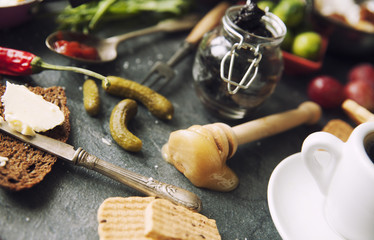 Table with food in breakfast or lunch: omelette, cabbage, oil, chili, ketchup, arugula, onion, garlic, noodles, cucumber, coffee, biscuits, orange, bread and butter