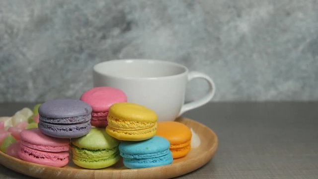 panning shot of white cup of hot coffee and colorful macaroons dessert food on dish