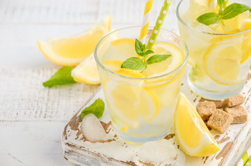 Cold refreshing summer drink with lemon and mint on wooden background.
