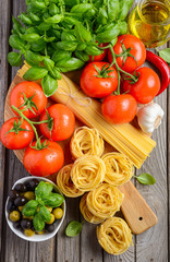 Pasta, vegetables, herbs and spices for Italian food on wooden background, top view