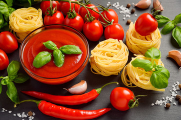 Tomato sauce with pasta and ingredients on black background