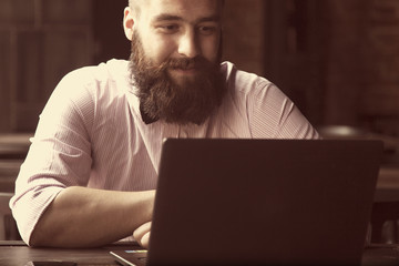 Portrait of a young bearded businessman working with laptop (Success, knowledge, victory, money)