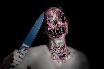  horrible scary zombie girl with a kitchen knife on black background with copyspace