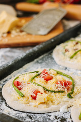 Cooking process of making mini pizza - small and personal, with cheese, tomatoes and asparagus.