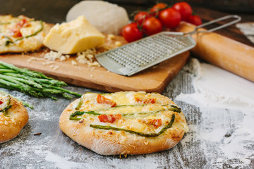 Fototapeta na wymiar Mini pizza with asparagus. Traditional small pizza for personal eating filling with cheese, tomatoes and asparagus.