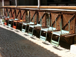 Umgedrehte Tische und Stühle mit Theke und Bar vor einem Restaurant im Sonnenschein in den Gassen...