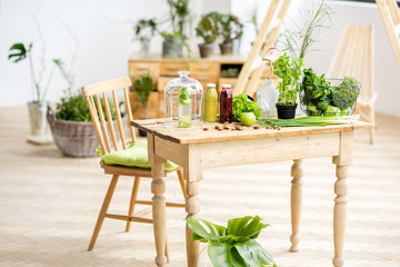Table full of healthy green food and smoothies at the beautiful interior with greenery