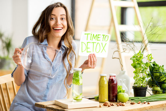 Beautiful woman sitting with healthy green food and drinks at home. Vegan meal and detox concept