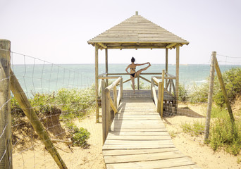 Woman doing yoga facing the ocean